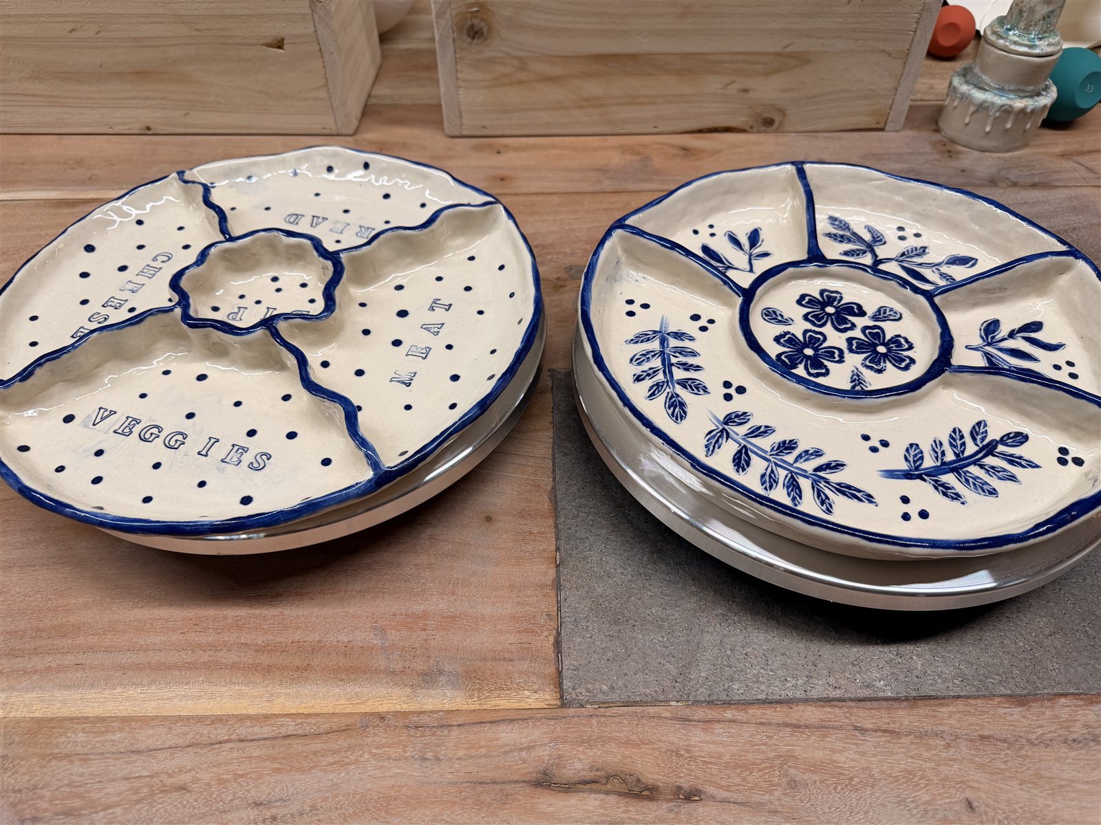 Two cream ceramic snack trays with blue divided sections, food labels and floral decoration